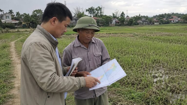 Cán bộ kỹ thuật và nông dân xem bản đồ dịch hại cây trồng Việt Nam ngoài đồng